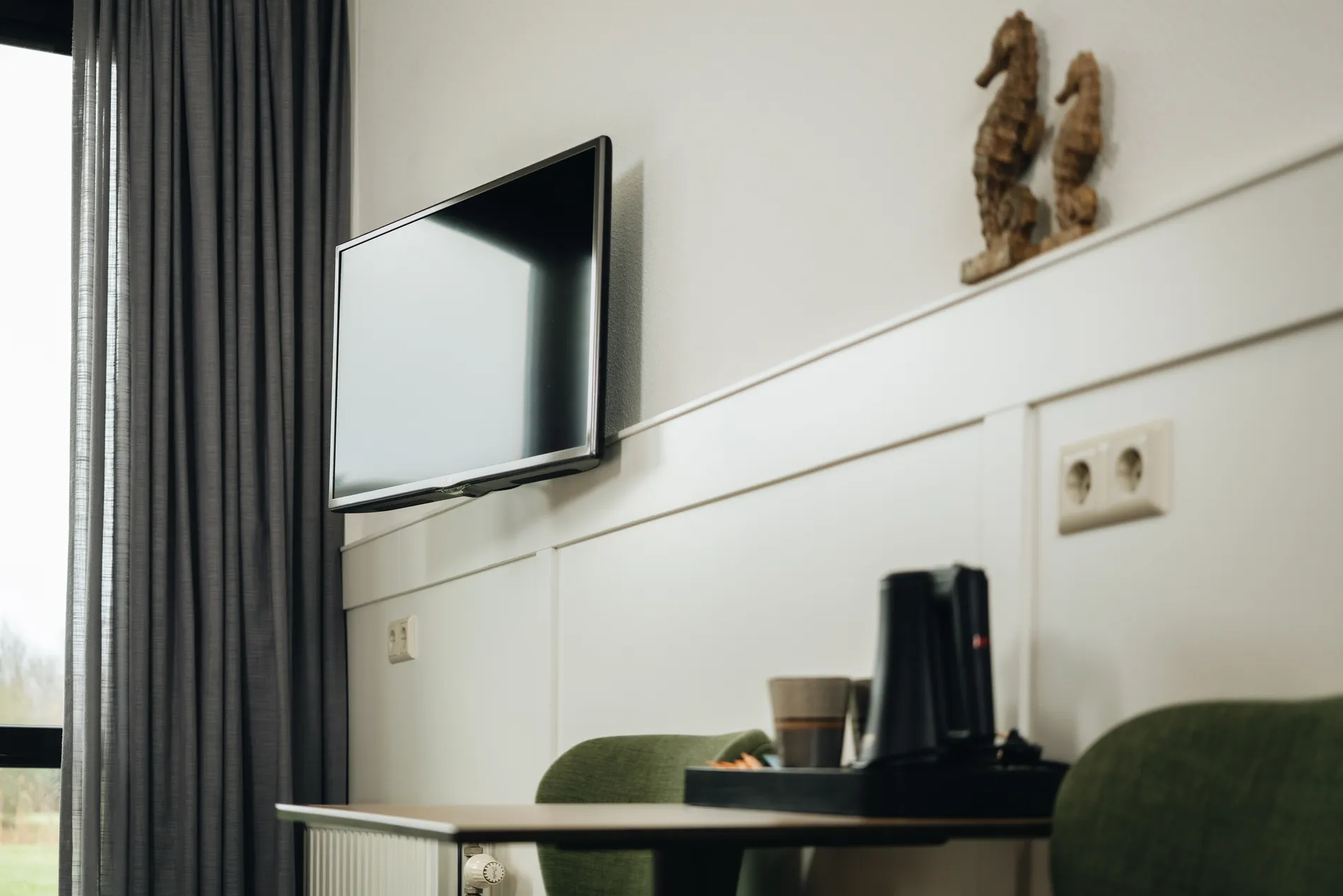 Kamerfaciliteiten bij Resort Land & Zee: aan de wand gemonteerde flatscreen-tv en een koffiecorner met decoratieve zeepaardjes.